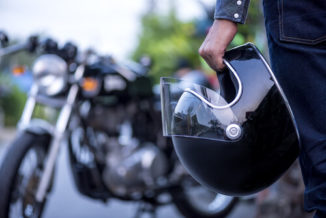 A motorcycle driver holding a helmet