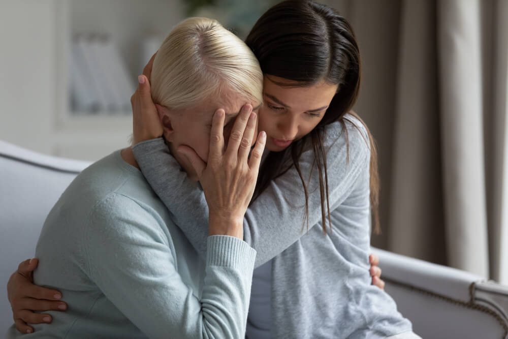Upset loving grown-up millennial daughter cuddling supporting depressed, stressed middle-aged mother.
