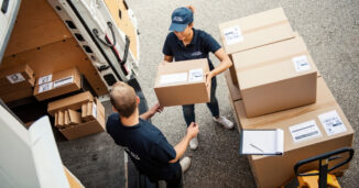two people, one woman and one man, unloading boxes from a van.