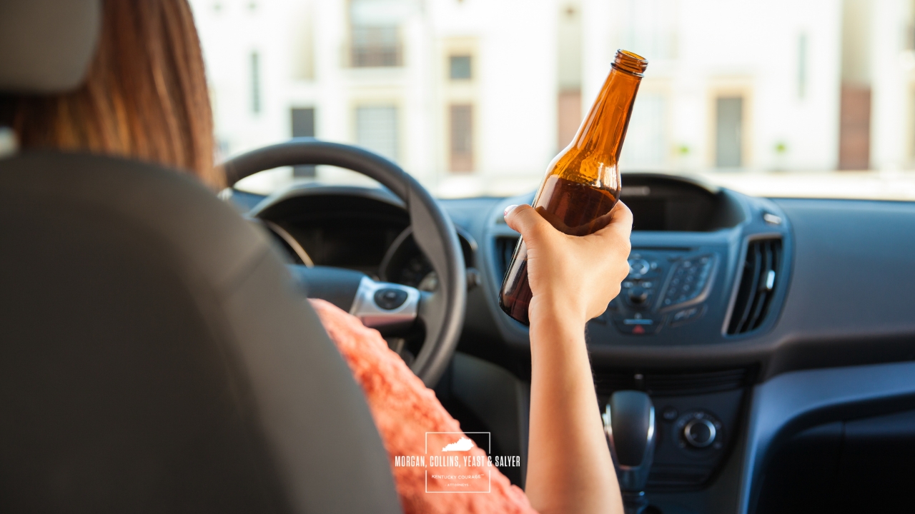 person driving with a glass bottle