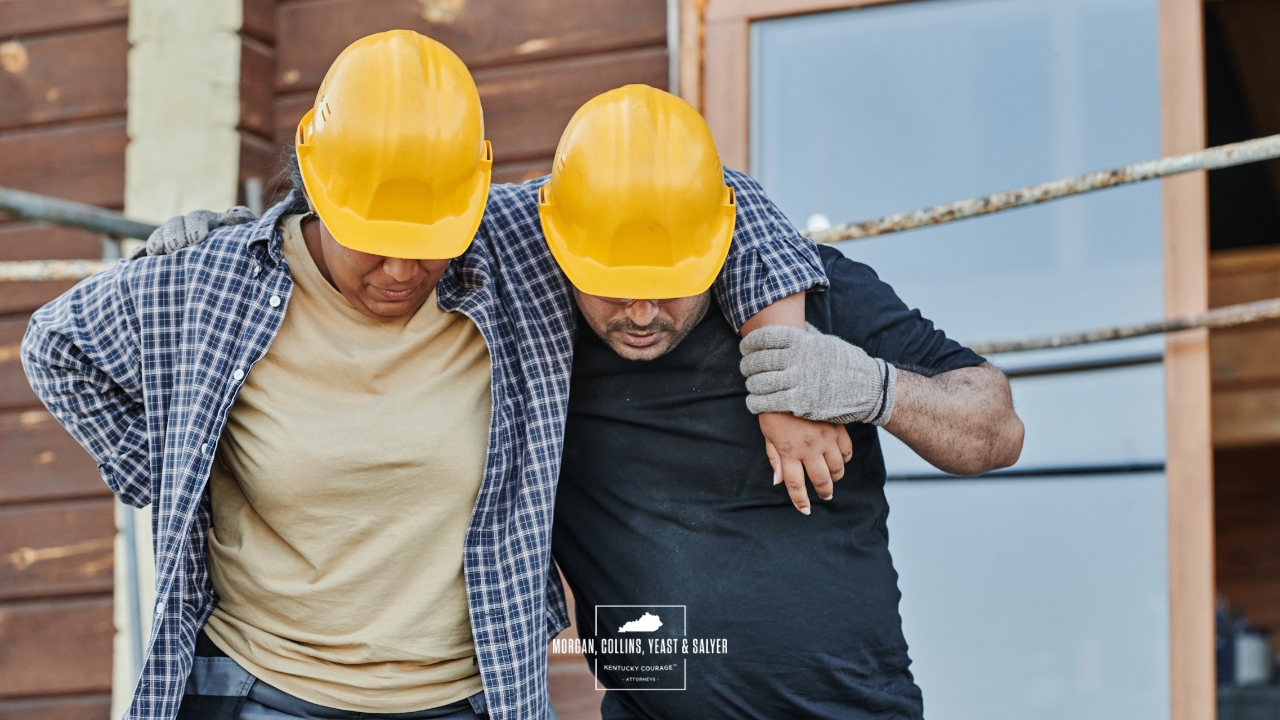 a construction worker helping a colleague up from an injury